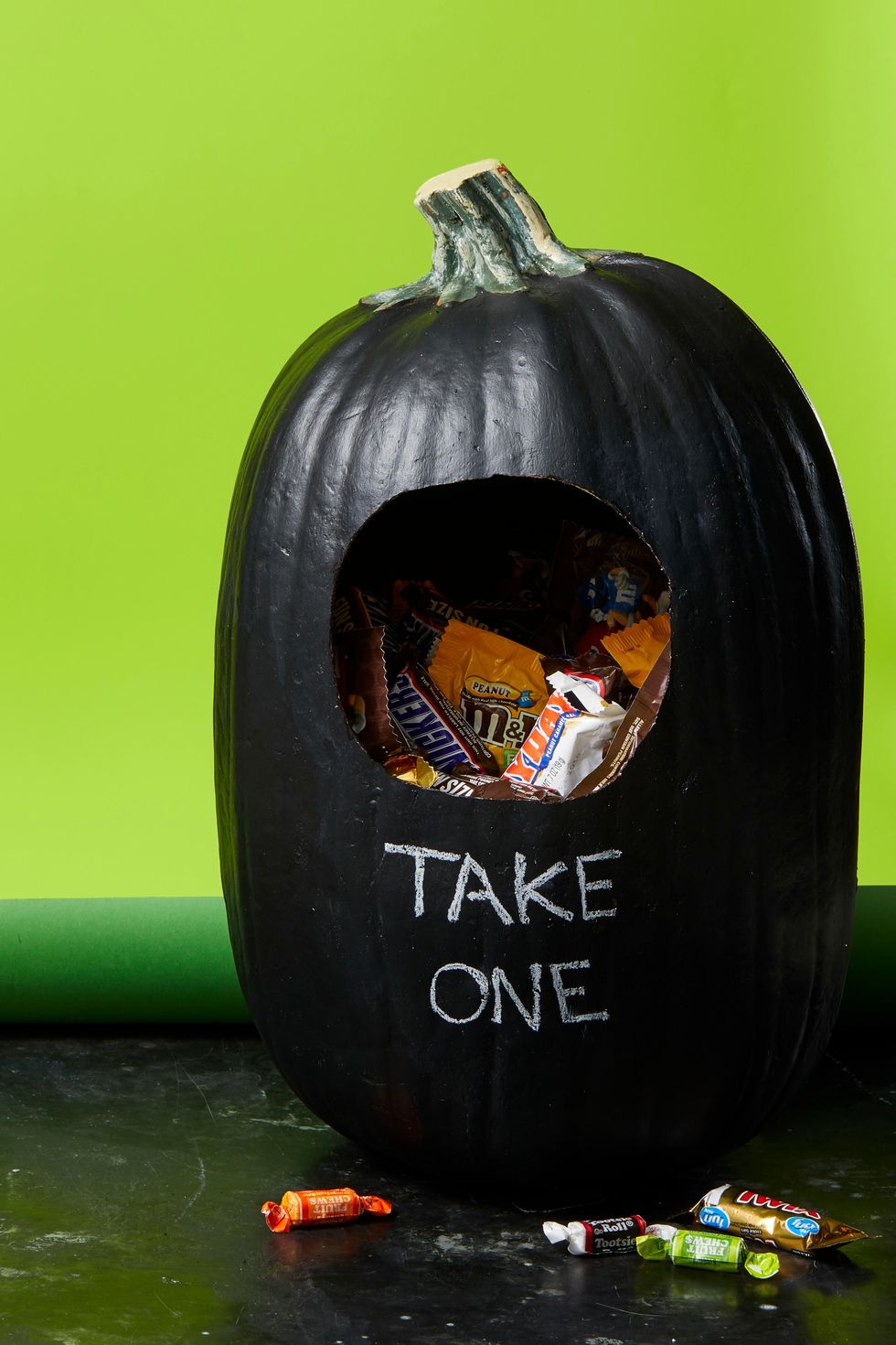 Black pumpkin with "Take One" written on it, filled with delicious chocolate—a tempting Halloween treat for all